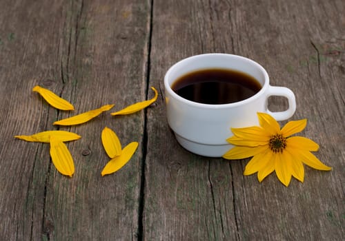still life a white cup of coffee, a yellow flower and petals, on a wooden table, a subject flowers and drinks