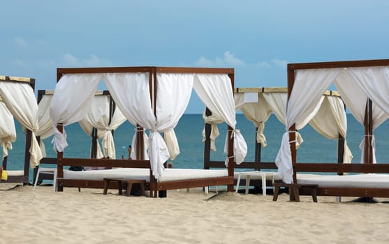 Canopies with a white cloth on a background of sea and sky. Focus on the main subject of the picture. Shallow depth of field.