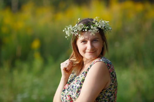 Pretty young woman with wreath on her head smiling and looking at the camera. Sunset light. Shallow depth of field. Focus on model.