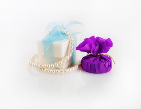 Conceptual festive still life. Gift box, soap and a pearl necklace.
