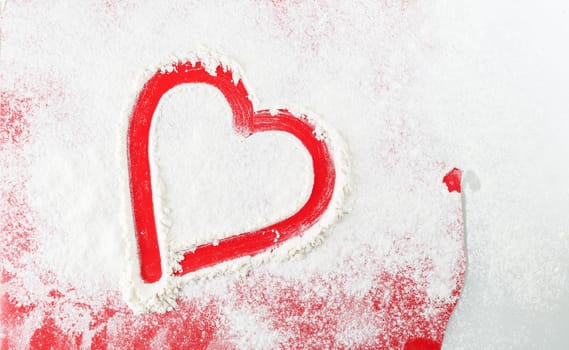 Stylized red heart, drawn in white flour. Top view.