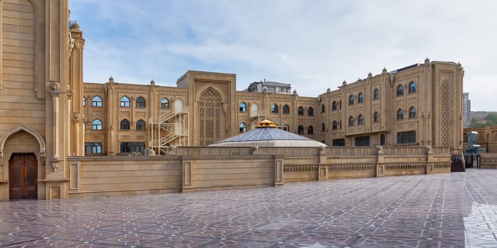 Baku Islamic University, located near Taza Pir Mosque, features intricate architectural designs. The scene reflects a blend of traditional and modern styles, highlighting the beauty of Baku