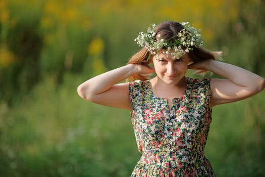 A smiling girl with a wreath on his head and straightens her hair looking at the camera. Sunset light. Shallow depth of field. Focus on eyes. Space for text.