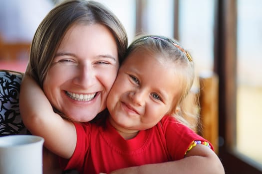 Happy smiling mother and little daughter. Close-up family portrait. Shallow depth of field.  Selective focus on the model's faces.