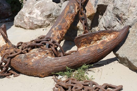 A large fragment of old weathered rusty ship anchor