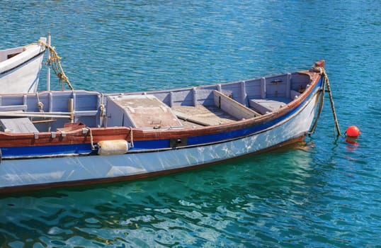 Old fishing boats painted in white on the water on a sunny summer day.