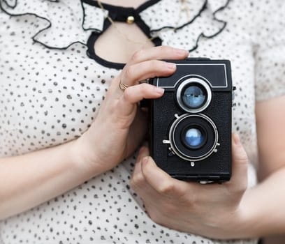 Old vintage camera in retro style in female hands. Shallow depth of field. Selective focus on camera.