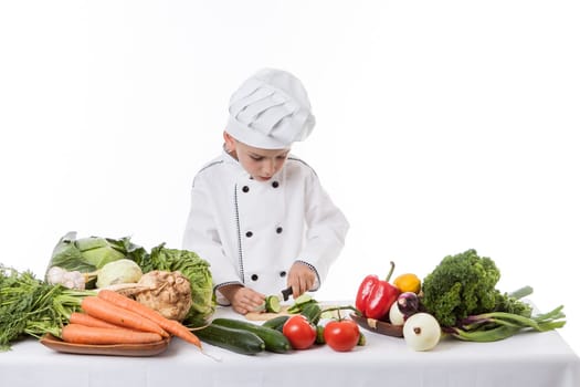 One little boy as chef cook making salad, cooking with vegetables. Isolated on white.