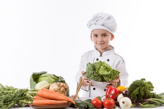 One little boy as chef cook making salad, cooking with vegetables. Isolated on white.