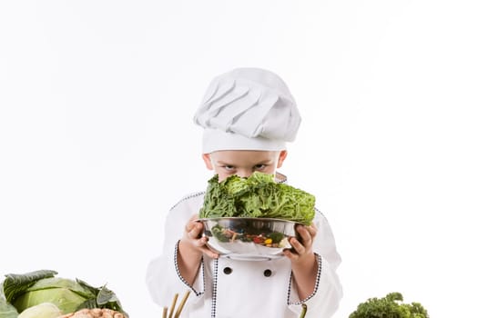 One little boy as chef cook making salad, cooking with vegetables. Isolated on white.