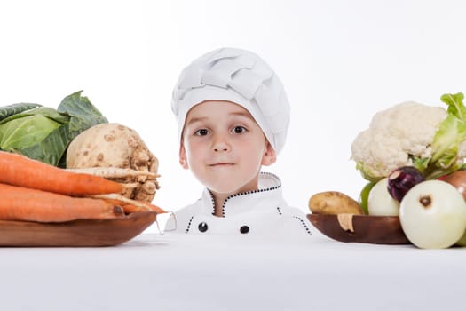 One little boy as chef cook making salad, cooking with vegetables. Isolated on white.