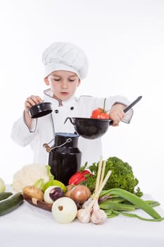 One little boy as chef cook making salad, cooking with vegetables. Isolated on white.
