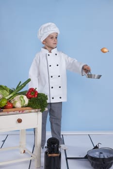 One little boy as chef cook making salad, cooking with vegetables. Isolated on white.