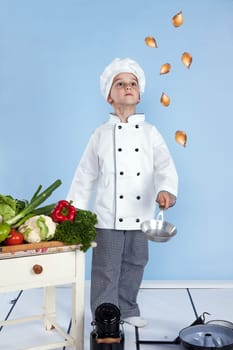 juggling with onions in a pan - One little boy as chef cook making salad, cooking with vegetables. Isolated on white.