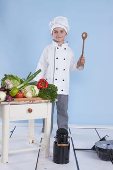 One little boy as chef cook making salad, cooking with vegetables. Isolated on white.