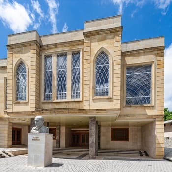 Shaki, Azerbaijan - May 15, 2024: At the entrance of Sheki State Drama Theatre, a beautifully designed building, stands the statue of Sabit Rahman, showcasing his contribution to Azerbaijani culture