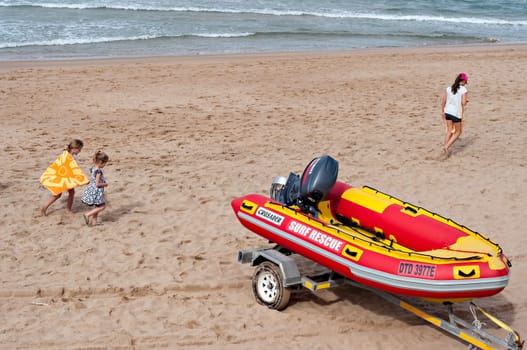 DURBAN, SOUTH AFRICA - JULY 09, 2016: Children playing on the beach near a surf rescue boat in Umhlanga Rocks