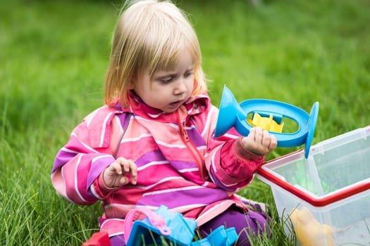 Little girl playing with her toys in the garden