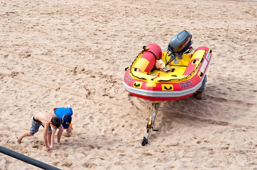 DURBAN, SOUTH AFRICA - JULY 09, 2016: Children playing on the beach near a surf rescue boat in Umhlanga Rocks