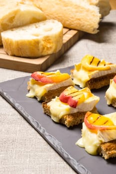 canapes, appetizer with grilled brie and nectarine plated on a slate dish