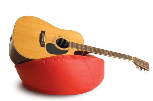 Classical guitar standing on a red stuffed chair isolated on white background