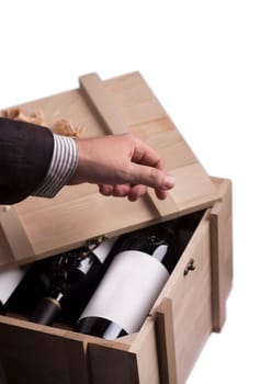 A hand choosing a bottle of wine from a wooden crate
