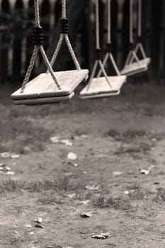 Vertical perspective view of three wooden child swings in the park with shallow depth of field
