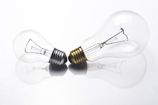 A small light bulb with silver screw and a large one with golden screw on white background