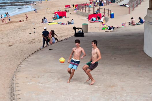 DURBAN, SOUTH AFRICA - JULY 09, 2016: Boys paying beach soccer near the Millennium Pier and lighthouse in Umhlanga Rocks