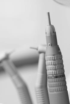 Black and white picture of a medical chrome water dispenser with a dentist chair in the background