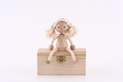 hand made wooden girl sitting on a wooden chest