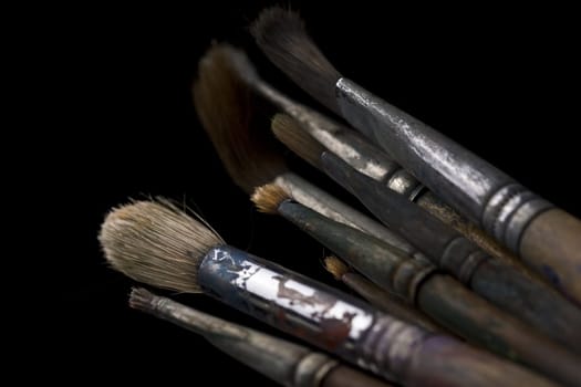 Set of heavily used painting brushes on black background