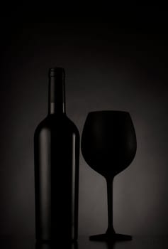 Black wine bottle and black glass of wine on black background