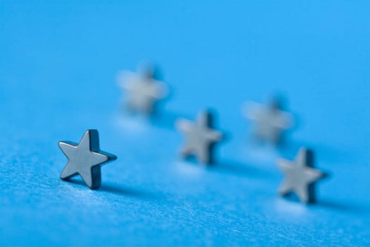 Five metal stars on blue background with shallow depth of field