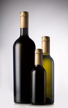 Wine bottles in different sizes with pilfers, screw cap. One large, two small.