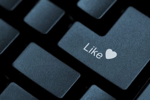 Horizontal close up of black keys on a keyboard with the word like and a heart icon on one of them