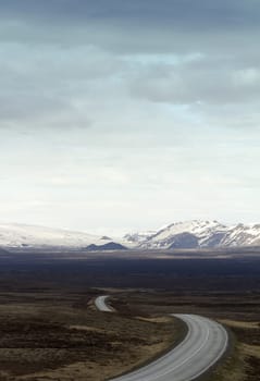 Vertical photo of a winding asphalt road going into the mountains in Thingvellir national park in Iceland