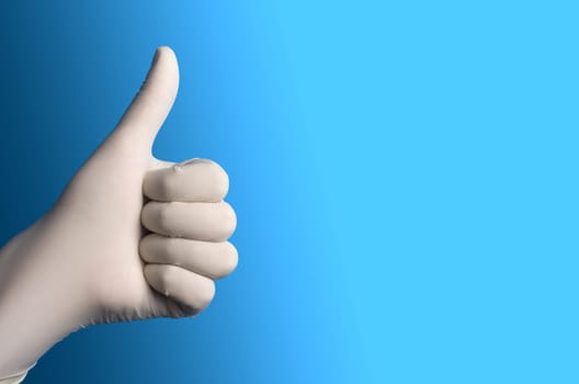 Hand with a white surgical glove showing the thumb up sign against a blue background