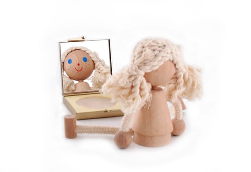 Horizontal photo of a wooden little doll with blue eyes looking in the mirror isolated on white background