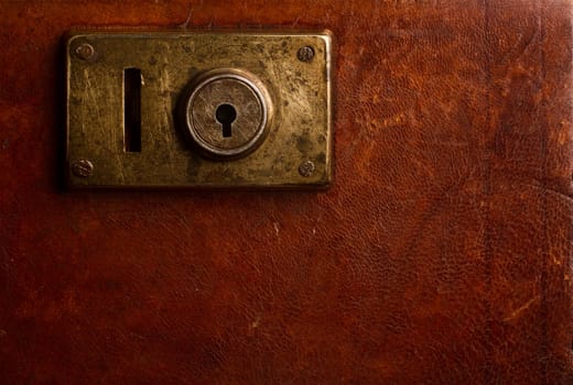 Horizontal close up of an old locking mechanism on a vintage suitcase made of brown leather