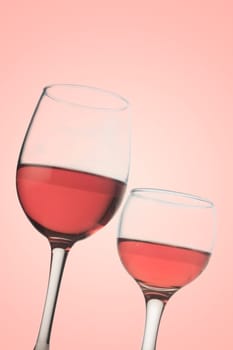 Vertical front view of two rose wine glasses isolated on pink background