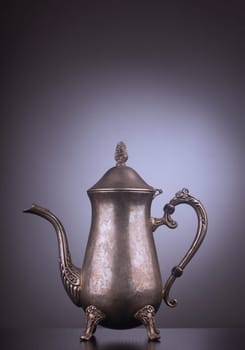 Silver vintage tea kettle with engravings on gray background