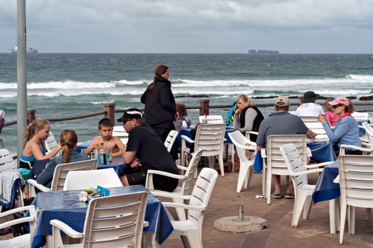 DURBAN, SOUTH AFRICA - JULY 09, 2016: Locals and tourists at a restaurant on the promenade at the beach in Umhlanga Rocks beach