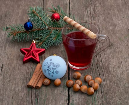 coniferous branch with Christmas tree decorations, tea, a star, nutlets and baking, the subject Christmas and New Year