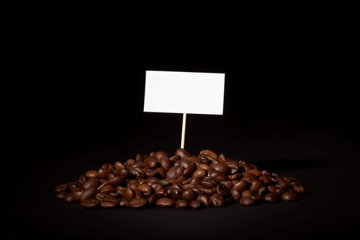 A pile of coffee beans with an empty sign on top of them shot on black background