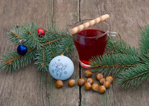 coniferous branch with Christmas tree decorations, tea and nutlets, the subject Christmas and New Year