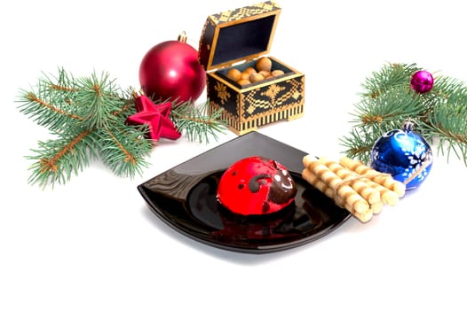 coniferous branch, red cake on a plate and nutlets, a still life the subject Christmas and New Year
