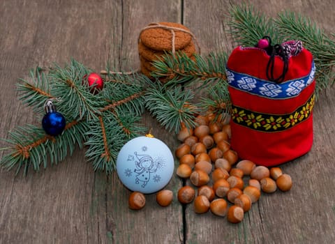 coniferous branch with Christmas tree decorations, a red gift bag and nutlets, the subject Christmas and New Year
