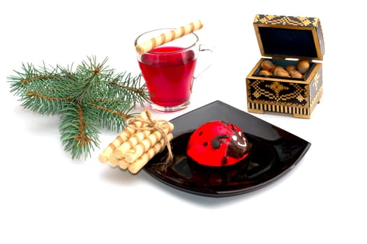 plate with red cake, tea, nutlets and a coniferous branch, a still life, the subject Christmas and New Year
