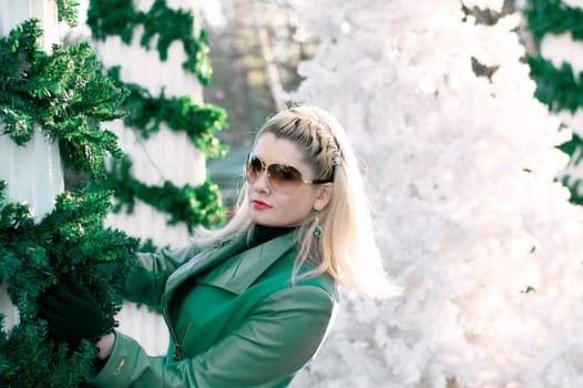 portrait of the beautiful woman in a green coat at the column braided by fir-tree branches, a subject the woman and holidays Christmas and New Year